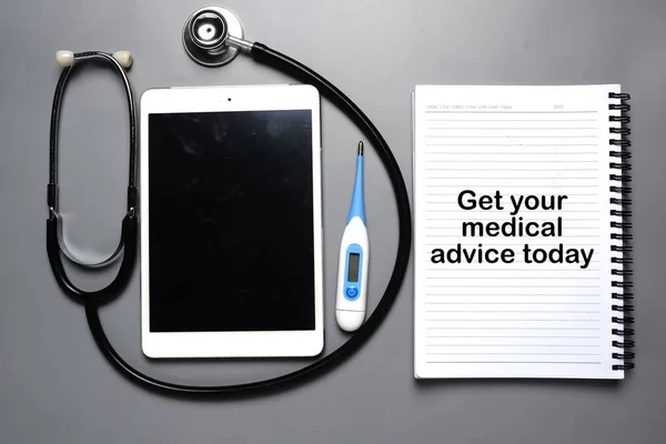 A picture of tab with stethoscope, thermometer and notebook written get your medical advice today.