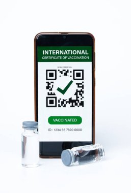 Üzerinde sahte Uluslararası Aşı Sertifikası ve iki doz aşı öngörüsü olan bir akıllı telefon resmi. Aşı oranı pek çok ülkede iyi değildir.