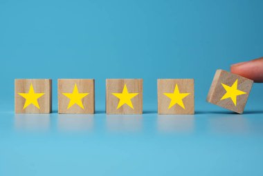 Mavi zemin üzerinde ahşap blok kullanarak 5 yıldız puanı veren el resmi