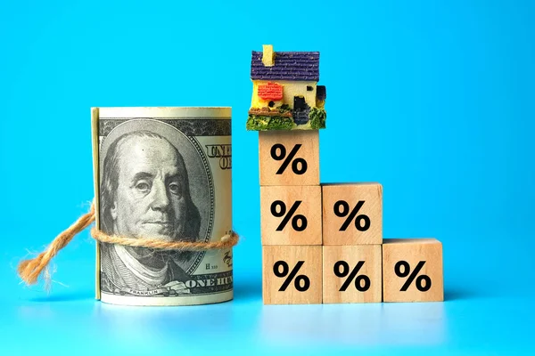 A picture of percentage on at all wooden block with miniature house and fake money. A symbol of high price of property caused by cost increase in every section especially commission.