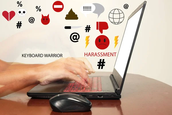 Selective focus of laptop with slow shutter and motion blur hand typing at laptop keyboard on the table with noise effect added. Symbol for cyber bullying concept