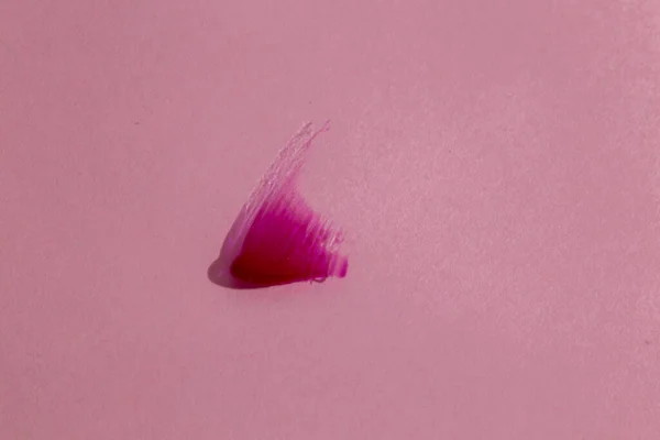 Pembe arka planda bir damla sıvı ruj. makro