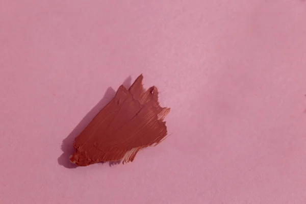Pembe arka planda bir damla sıvı ruj. makro