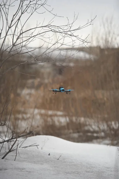 Çeyrek helikopter ağaçların arasında uçuyor.