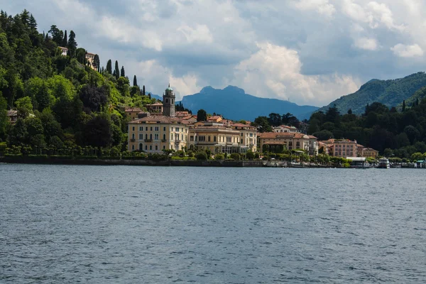 Vista de la línea de costa del Lago de Como, Italia, región de Lombardía. Paisaje italiano, con la montaña y la ciudad con muchos edificios de colores en la orilla — Foto de Stock