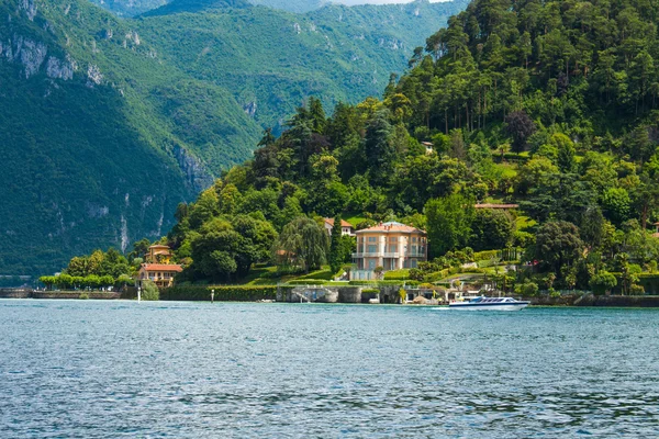 Vista de la línea de costa del Lago de Como, Italia, región de Lombardía. Paisaje italiano, con la montaña y la ciudad con muchos edificios de colores en la orilla — Foto de Stock