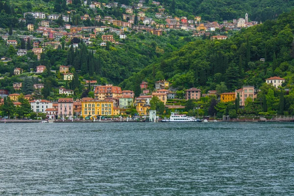 Vista de la línea de costa del Lago de Como, Italia, región de Lombardía. Paisaje italiano, con la montaña y la ciudad con muchos edificios de colores en la orilla — Foto de Stock