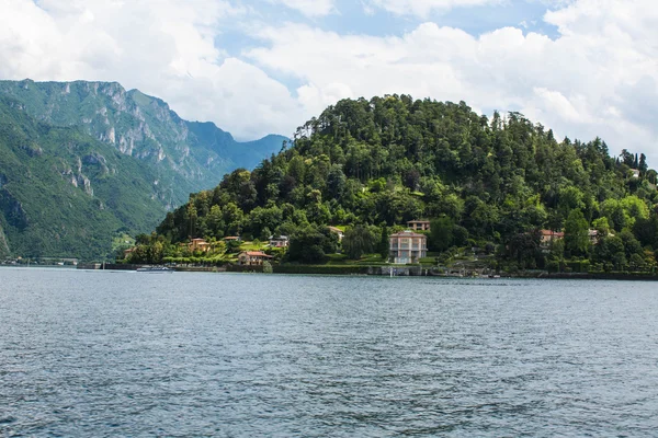 Vista na linha costeira do Lago de Como, Itália, região da Lombardia. Paisagem italiana, com Montanha e cidade com muitos edifícios coloridos na costa — Fotografia de Stock