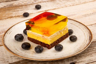 Tahta bir masada sarı jöle ve meyveli kek, ananas ve çilek.