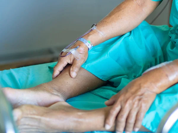 Hand of senior man patient is giving blood during treat anemia in patient. Asian old man patient sitting on bed in the hospital. Health care concept