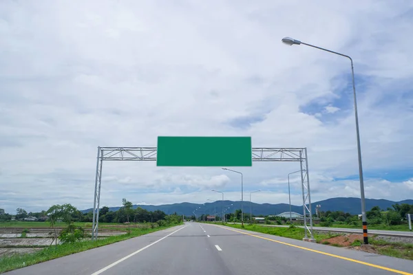 Boş bir otoyol tabelasıyla tarlaların arasındaki boş yol manzarası. Metin için yeşil reklam panosu