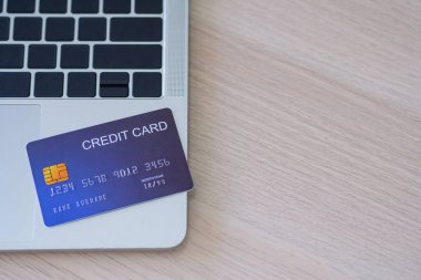 Mavi kredi kartının yakın plan bir görüntüsü dizüstü bilgisayarda. Çevrimiçi alışveriş için hazırlanın. Kredi kartıyla ödeme yaparak ürünleri internetten sipariş et. E-ticaret ve para elektroniği kavramı