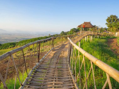 Dağların arka planına sahip bambu köprüsünün manzara manzarası.
