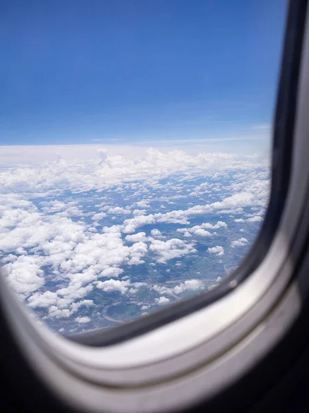 Aerial view of lands and clouds seen through the airplane window.