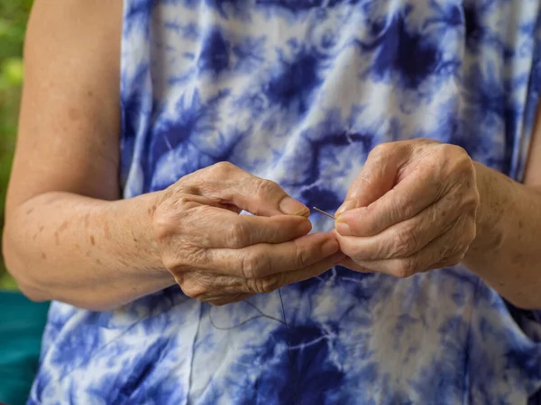 Руки Пожилой Женщины Пытающейся Натянуть Нитку Иглу Сидя Стуле Гостиной — стоковое фото