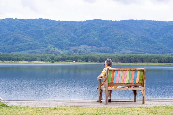 Vista Trasera Una Mujer Mayor Sentada Silla Lado Del Lago — Foto de Stock