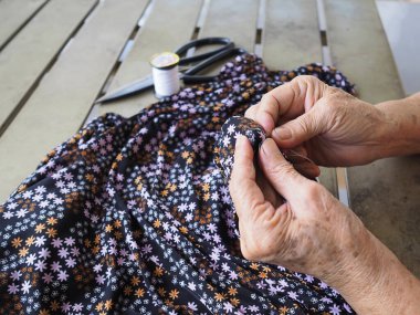 Elleri yakın plan, yaşlı kadın dikiş bezi iğnesine iplik geçirmeye çalışıyor. Mesaj için yer var. Yaşlılar ve rahatlama kavramı.