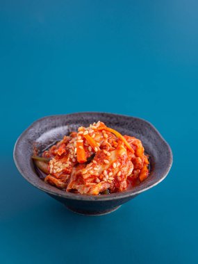 Geleneksel Kore yemeği (Kimchi) mavi arka planda bir kasede. Mesaj için yer var. Kore yemekleri kavramı..