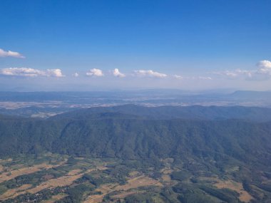 Uçak penceresinden görünen dağların ve bulutların havadan görünüşü.