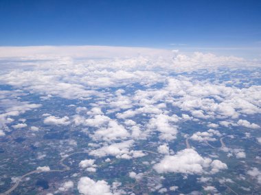 Uçak penceresinden görülen tarımsal alan, nehir ve bulutların havadan görünüşü.