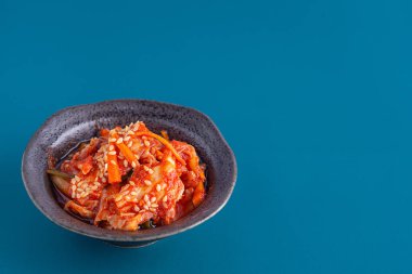 Geleneksel Kore yemekleri (Kimchi) mavi arka planda bir kasede. Mesaj için yer var. Kore yemekleri kavramı..