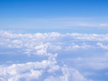 Gökyüzü ve bulutların hava görüntüsü uçak penceresinden görülür..