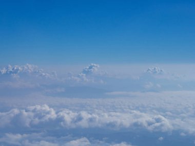 Uçak penceresinden görülen bulutlu hava manzarası.