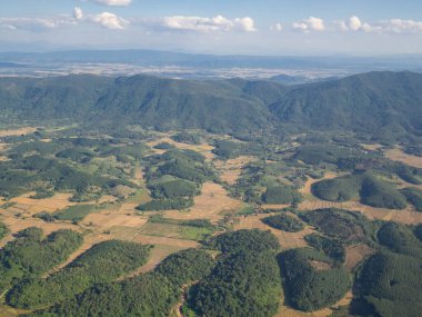 Uçak penceresinden görünen dağların ve bulutların havadan görünüşü.