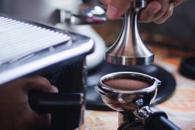 Barista 'nın yakın çekimi, kahve makinesini kurcalayarak ütülüyor. Kahveyi adım adım yapma süreci.