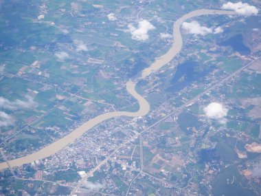 Uçak penceresinden görülen kara ve bulutların havadan görünüşü.