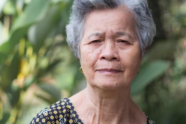 Yaşlı bir kadın bahçede dikilirken gülümseyip kameraya bakıyor. Mesaj için yer var. Yaşlılar ve sağlık hizmetleri kavramı