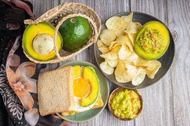 Tam buğday ekmeği ve kızarmış yumurta ve avokado dilimlenmiş guacamole. Tahta masada patates cipsi ve taze organik guacamole. Üst Manzara. Sağlıklı meyve kavramı