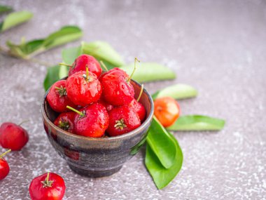 Taş zeminde yaprakları olan bir seramik kasede olgun kırmızı kirazlar. Mesaj için yer var. Tatlı organik meyveler. Sağlıklı meyve kavramı