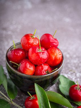 Taş zeminde yaprakları olan bir seramik kasede olgun kırmızı kirazlar. Mesaj için yer var. Tatlı organik meyveler. Sağlıklı meyve kavramı