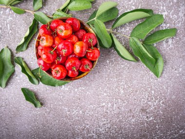 Taş zeminde yaprakları olan seramik bir kasede olgun kırmızı kirazların üst görüntüsü. Mesaj için yer var. Tatlı organik meyveler. Sağlıklı meyve kavramı