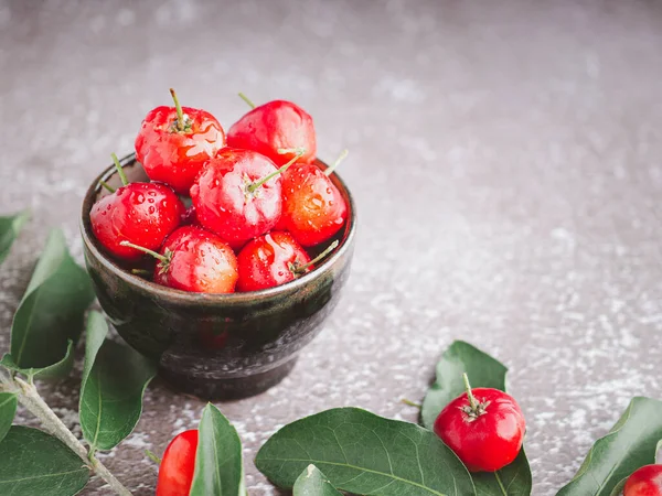 Taş zeminde yaprakları olan bir seramik kasede olgun kırmızı kirazlar. Mesaj için yer var. Tatlı organik meyveler. Sağlıklı meyve kavramı
