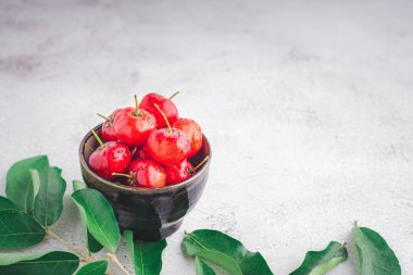 Taş zeminde yaprakları olan bir seramik kasede olgun kırmızı kirazlar. Mesaj için yer var. Tatlı organik meyveler. Sağlıklı meyve kavramı