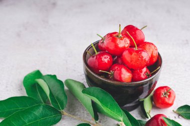 Taş zeminde yaprakları olan bir seramik kasede olgun kırmızı kirazlar. Mesaj için yer var. Tatlı organik meyveler. Sağlıklı meyve kavramı