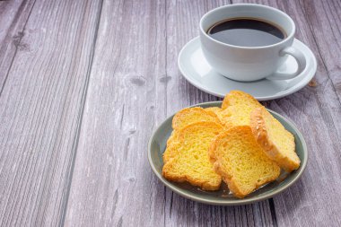 Çıtır tereyağlı tost ve ahşap masada beyaz bir kahve fincanı.