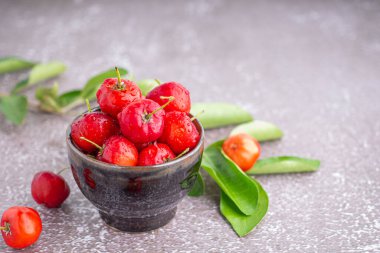 Taş zeminde yaprakları olan bir seramik kasede olgun kırmızı kirazlar. Mesaj için yer var. Tatlı organik meyveler. Sağlıklı meyve kavramı