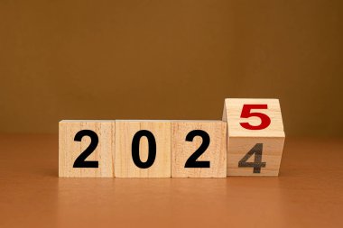 Countdown to 2025. Wooden cubes with the letters 2024 changed to 2025 on a table with brown background. Space for text. Business plan concept