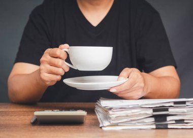 Genç bir adam masada otururken bir fincan kahve tutuyor. Yakın plan fotoğraf. İçecek ve rahatlama kavramı