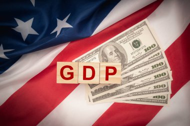 Gayrisafi Yurtiçi Hasıla ya da gayrisafi Yurtiçi Hasıla. Amerikan bayraklı banknotlarda tahtadan küpler. İş ve GSYİH büyümesi, yerli ürün konsepti. Üst görünüm