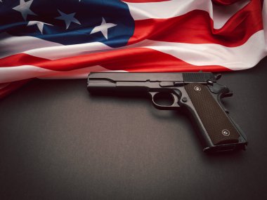 Amerikan bayrağının bir parçası ve siyah arka planda bir tabanca. Üst Manzara. Metin için boşluk
