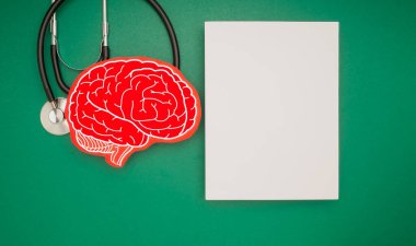 Beyin şekli sembolü, steteskop ve yeşil arka planda beyaz bir kağıt. Alzheimer, Parkinson, bunama, felç, nöbet ya da akıl sağlığı. Nöroloji ve Psikoloji