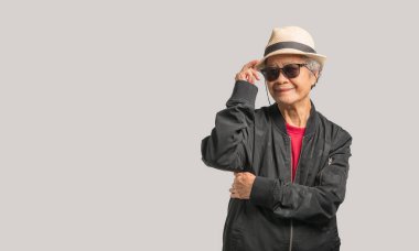 Siyah gözlüklü, son sınıf güzeli bir kadın ve gri arka planda dururken kameraya gülümseyen bir şapka takıyor. Yaşlılar ve rahatlama konsepti