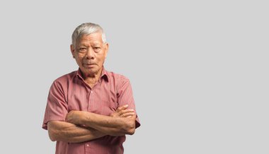 Gri bir arka planda dururken kameraya gülümseyen ve kollarını kavuşturan üst sınıf bir adamın portresi. Mesaj için yer var. Yaşlılar ve sağlık konsepti