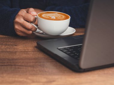 Masada otururken bir fincan kahve tutarken. Yakın plan fotoğraf.