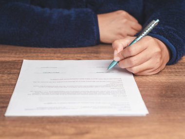 İmza konsepti. Ofiste masada otururken kazaklı bir iş adamı kira sözleşmesi ya da anlaşma imzalıyor. Yakın plan fotoğraf. İş ve belge yönetimi kavramı