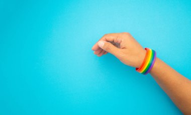 Mavi arka planda bileklikte gökkuşağı bilekliğinin üst görüntüsü. Yakın plan fotoğraf. Cinsiyet çeşitliliği kavramı